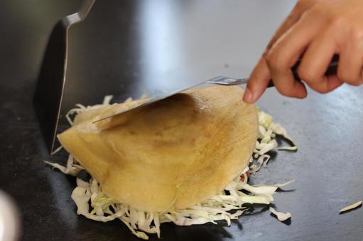 鉄板でお好み焼きを作っている 鉄板でお好み焼きを作っているの写真