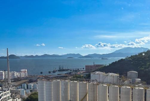 海と山を背景にした工場設備と青空の風景 海と山を背景にした工場設備と青空の風景 海,山,青空の写真素材