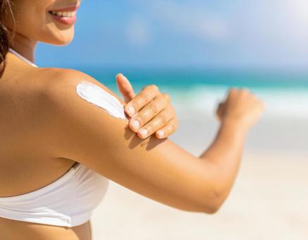 海で日焼け止めを塗る女性の写真