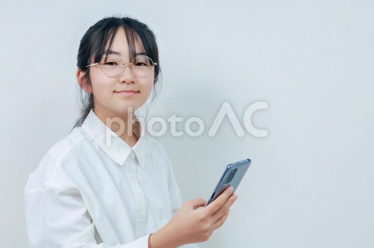 カメラ目線で微笑むスマホを持った女の子 女性,小学生,少女の写真素材