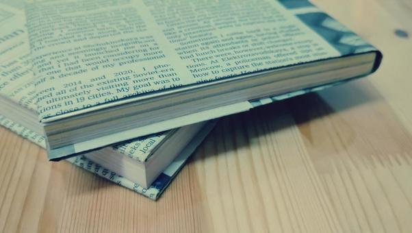英字新聞のブックカバーをつけた書籍 英字新聞のブックカバーをつけた書籍 英字新聞,本,古本の写真素材