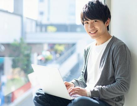 ノートパソコンを操作する若い男性 ノートパソコンを操作する若い男性の写真