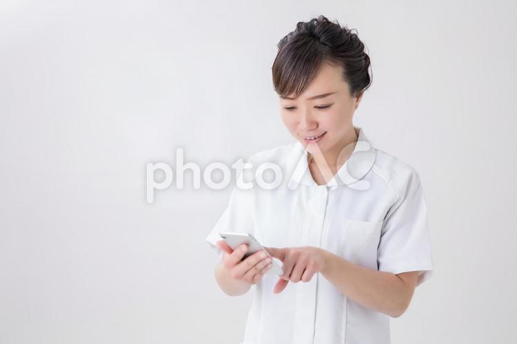 スマホを使う白衣の女性 メール,看護師,アプリの写真素材