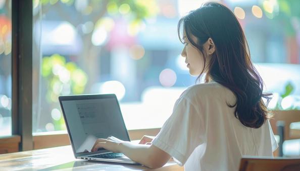 カフェでノートパソコンを使う日本人女性 カフェでノートパソコンを使う日本人女性の写真