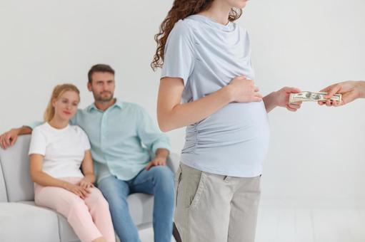 お金を受け取る妊婦と後ろに夫婦 お金を受け取る妊婦と後ろに夫婦の写真