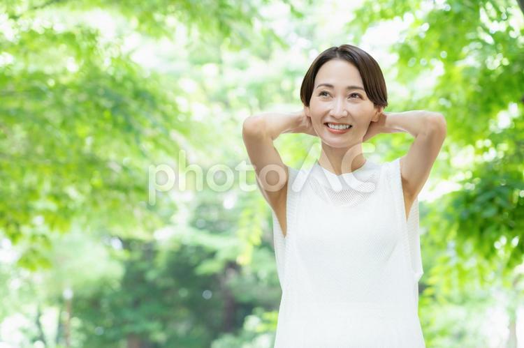 新緑の中でスキンケアをするミドルの女性 ビューティー,女性,スキンケアの写真素材