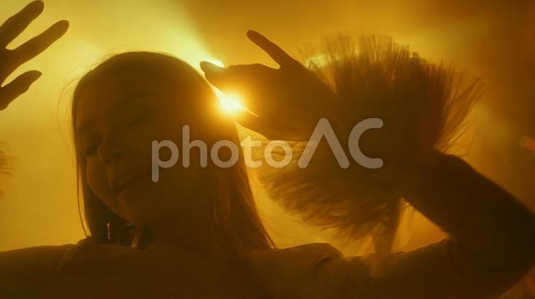黄色の照明に照らされる笑顔の女性 女性,踊る,ポーズの写真素材