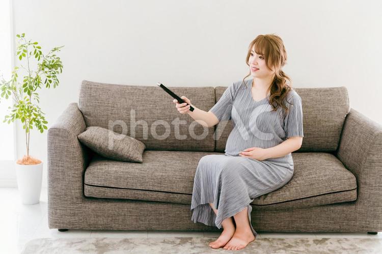 産休中に家でテレビを見るアジア人女性 テレビ,リモコン,妊婦の写真素材