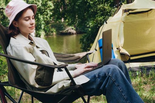 椅子に座り笑顔を見せる人物 女性,外国人,キャンプの写真素材