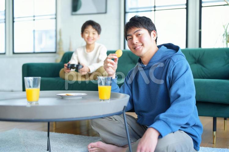 カメラ目線で笑顔でおやつを食べる親子 親子,男の子,小学生の写真素材
