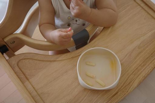 おやつを手づかみで食べる赤ちゃん ハイローチェア,おやつ,赤ちゃんの写真素材
