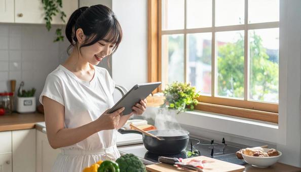 レシピを見ながら料理する日本人の若い女性 レシピを見ながら料理する日本人の若い女性の写真