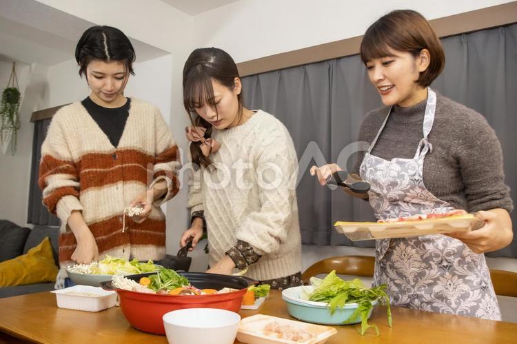 鍋にトングでこれから肉をいれる女性1 女性,鍋パーティー,女子会の写真素材