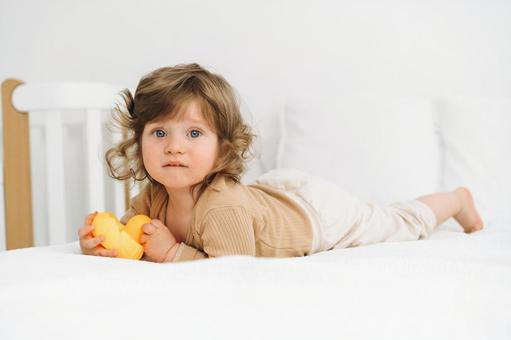 アヒルの玩具を持ちカメラ目線の子供 アヒルの玩具を持ちカメラ目線の子供 赤ちゃん,かわいい,腹ばいの写真素材