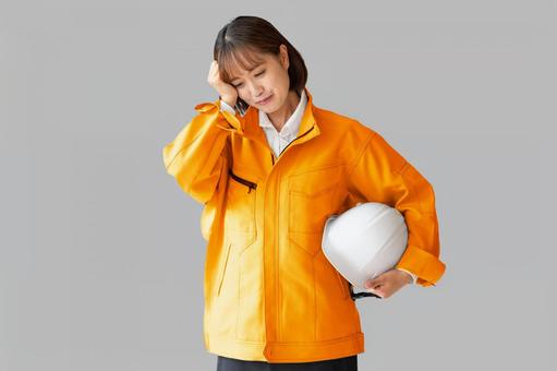 頭を抱える女性作業員 作業着,作業服,困るの写真素材