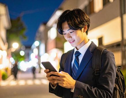 夜の住宅街でスマホを操作する男子高校生 夜の住宅街でスマホを操作する男子高校生の写真