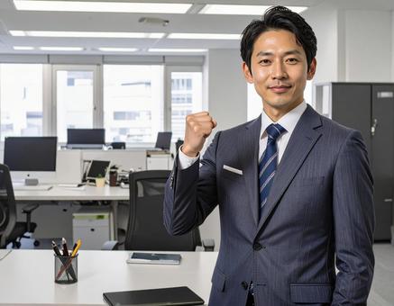 オフィスでガッツポーズするスーツの男性 オフィスでガッツポーズするスーツの男性の写真