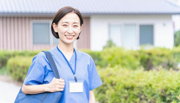 訪問看護で訪問先の住宅に笑顔で立つ女性 訪問看護で訪問先の住宅に笑顔で立つ女性の写真