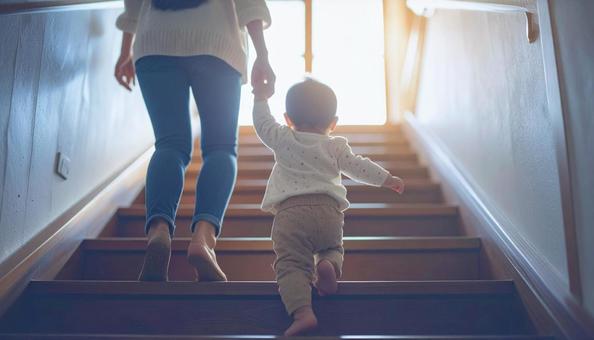 階段を下りるのが楽しい子供と支える母親 階段を下りるのが楽しい子供と支える母親の写真
