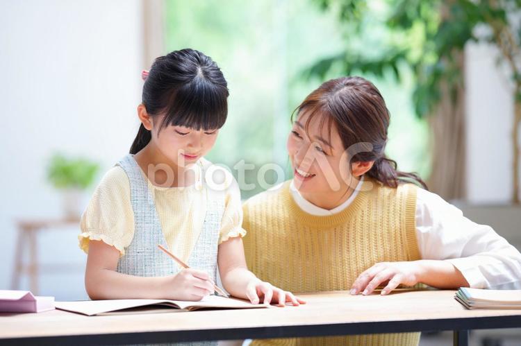 宿題中の娘を見る笑顔の母 娘,真剣,母の写真素材