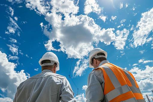 現場で働く建設作業員の後ろ姿と青空 現場で働く建設作業員の後ろ姿と青空の写真
