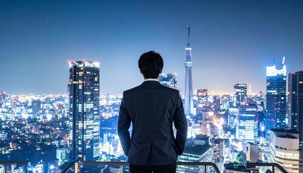 都市の夜景を背景に佇むビジネスマン 都市の夜景を背景に佇むビジネスマンの写真