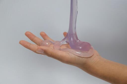 容器から手のひらに注がれる紫色のスライム スライム,手,流れるの写真素材