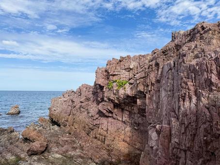 海岸にそびえる赤茶色の岩壁と青空の風景 岩,海岸,自然の写真素材