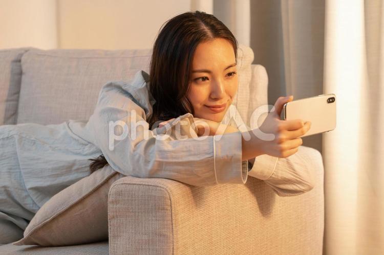 寝室で携帯を見る女性 女性,若い,夜の写真素材