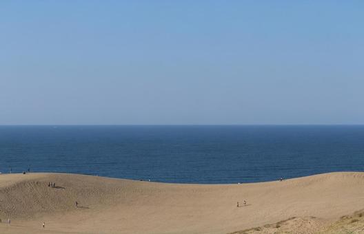 晩秋の青空と海をバックの砂丘に上る観光客 晩秋の青空と海をバックの砂丘に上る観光客の写真