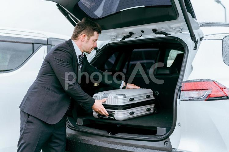 車のトランクにスーツケースを入れる男性 トランク,ラゲッジ,スーツケースの写真素材
