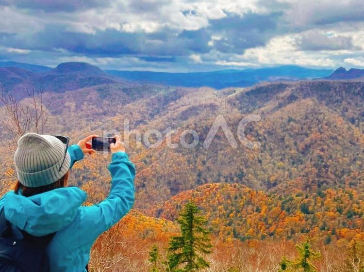 晩秋の紅葉の山頂で記念撮影をする後ろ姿 山,紅葉,晩秋の写真素材