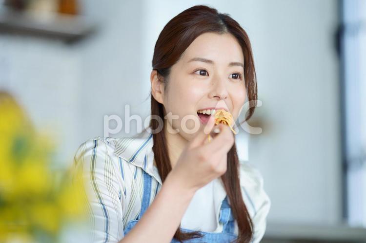 ダイニングテーブルでエプロンをしたままパスタを食べる女性 女性,日本人,1人の写真素材