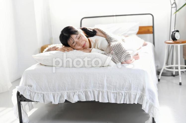 ベッドでうつ伏せで寝るアジア人の若い女性 睡眠,ベッド,女性の写真素材