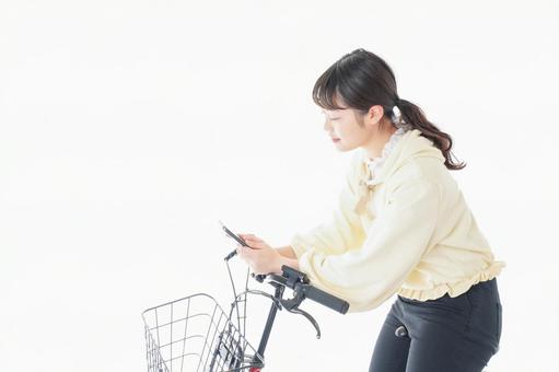 自転車でスマホを使う若い女性 自転車でスマホを使う若い女性 マナー違反,スマートフォン,私服の写真素材