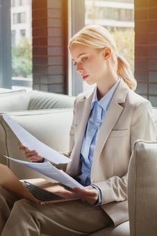 オフィスのソファで資料を見る女性 ビジネスウーマン,ビジネス,女性の写真素材