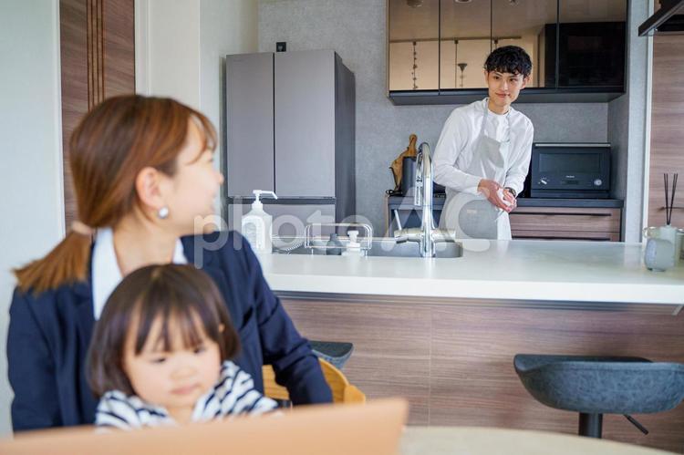 朝食準備中の男性とパソコンをする女性 女性,母,こどもの写真素材