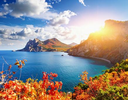 空と太陽、そして海と紅葉している山々 空と太陽、そして海と紅葉している山々の写真
