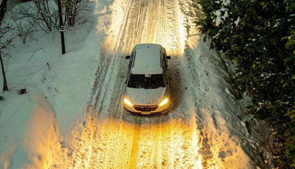 大雪が降った翌日の雪が積もった道を走る車 大雪が降った翌日の雪が積もった道を走る車の写真
