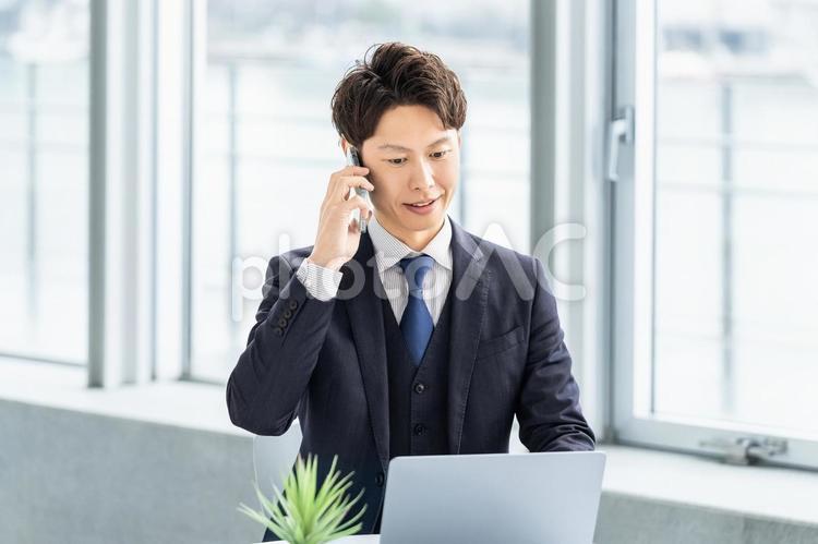 スマホで通話をする笑顔の男性ビジネスマン 男性,ビジネス,ビジネスマンの写真素材