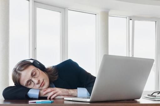 ヘッドホンを装着して机の上で寝る男性 男性,外国人,寝るの写真素材