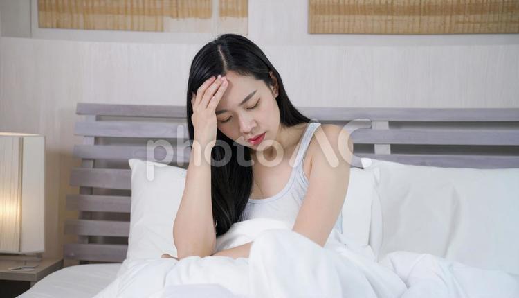 起床時に寝不足と疲労と体調不良の女性 偏頭痛,風邪,倦怠感の写真素材