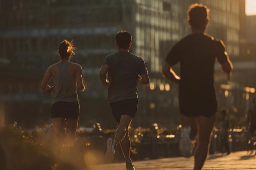 都会の夕暮れ時にジョギングを楽しむ若者 都会の夕暮れ時にジョギングを楽しむ若者の写真