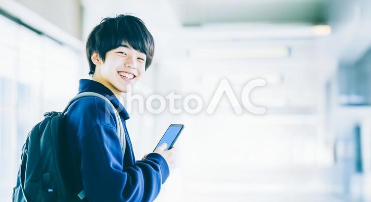 スマホを持ってほほえむアジア人の男子学生 男子学生,学生,若者の写真素材