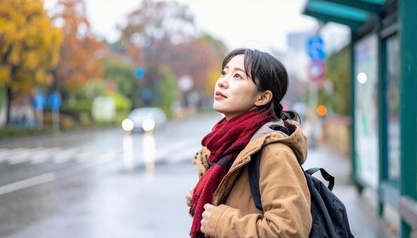 雨の中バス停でバスを待つ日本人女性 雨の中バス停でバスを待つ日本人女性の写真