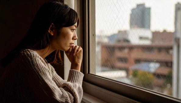 困った顔で手を顎に当てる若い女性の写真