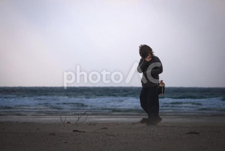 ＜素材＞冬の海で砂嵐から身を守る女性 女性,人物,風景の写真素材