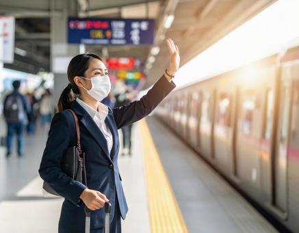 駅のホームで電車を見送る女性 駅のホームで電車を見送る女性の写真