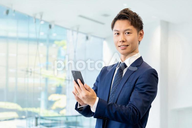 スマホを持つ笑顔の男性ビジネスマン 男性,スマホ,ビジネスの写真素材