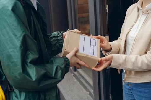 届け先の女性に配達物を渡す配達員 配達,デリバリー,配送の写真素材